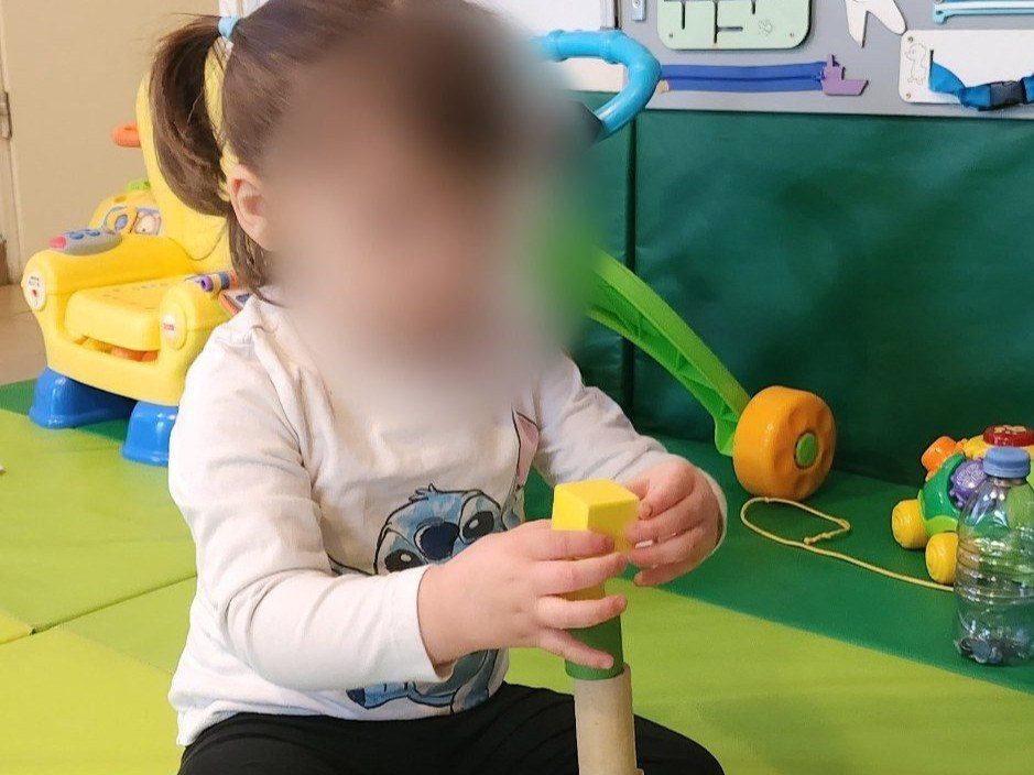 Une petite fille empile des cubes en bois sur les tapis de motricité, dans le coin d'éveil de l'assistante maternelle à Angerville